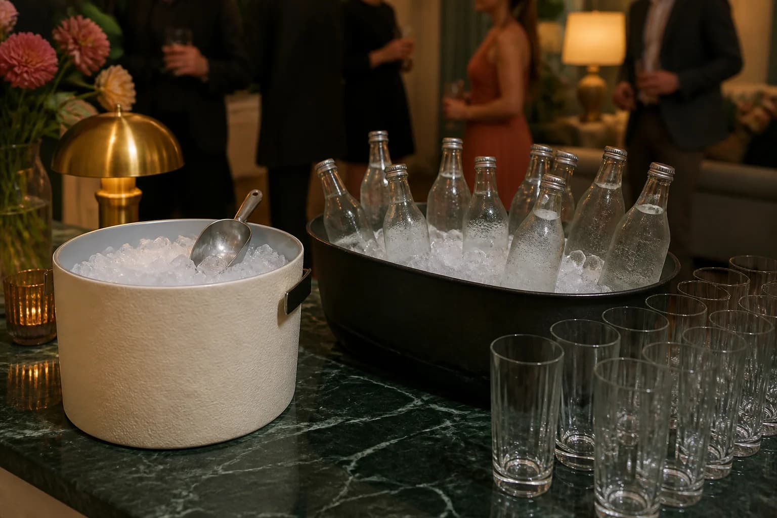 A clean serving-ice bucket with its own scoop stands apart from a wider tub used to chill closed mixer bottles at a party.