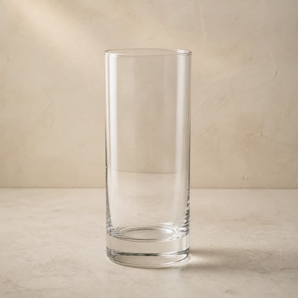 An empty clear highball glass with tall straight sides and a substantial base.
