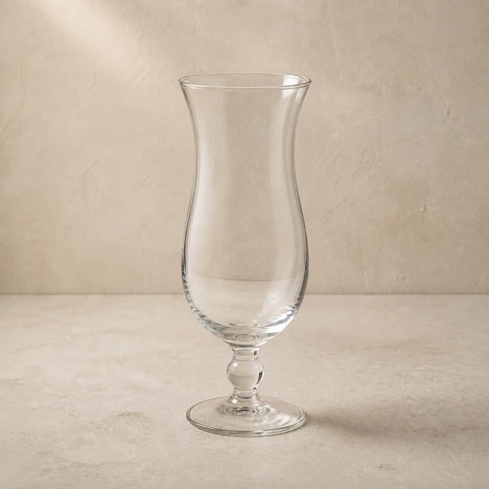 An empty clear hurricane glass with a tall curved bowl, flared rim and short stem.
