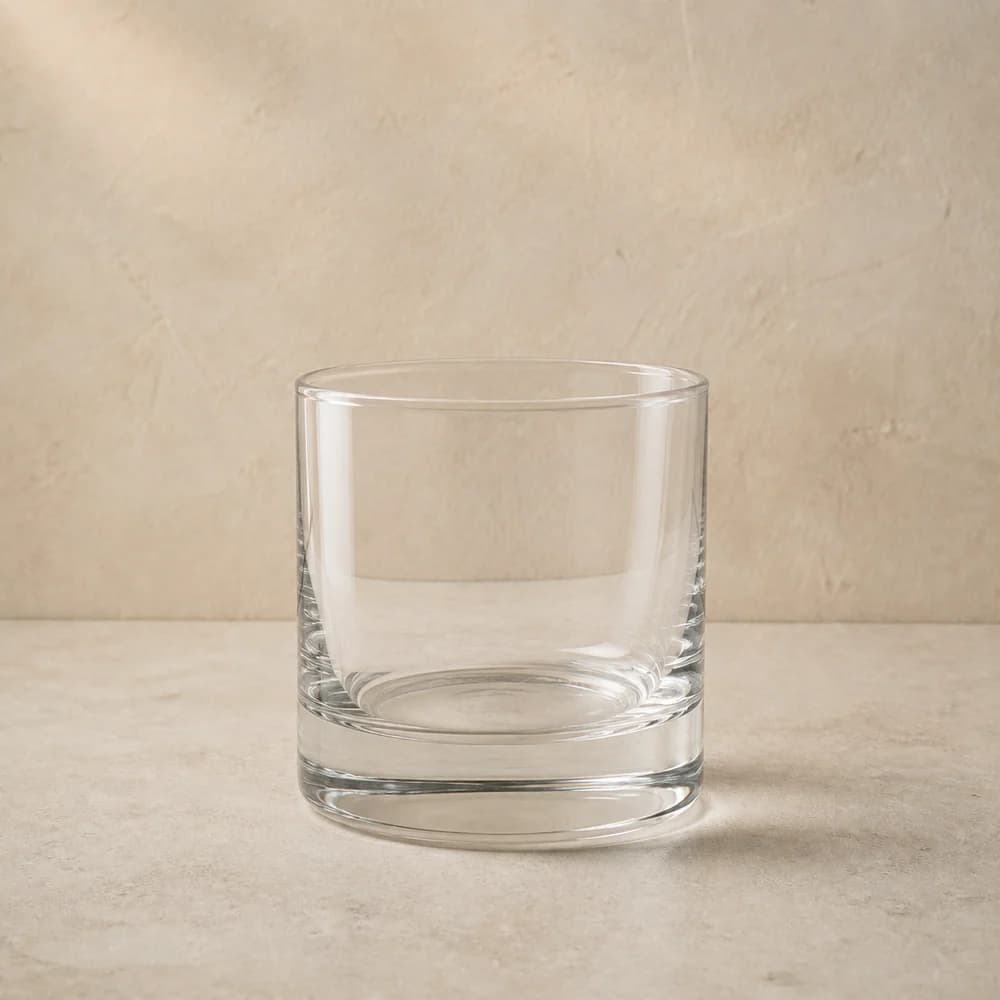 An empty clear rocks glass with low straight sides and a heavy base.