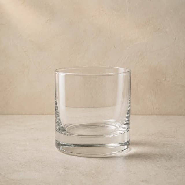 An empty clear rocks glass with low straight sides and a heavy base.