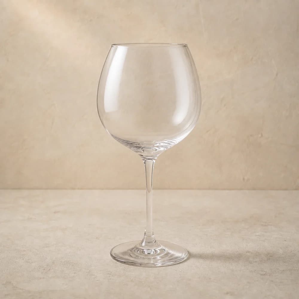 An empty clear large wine glass with a generous rounded bowl and slender stem.