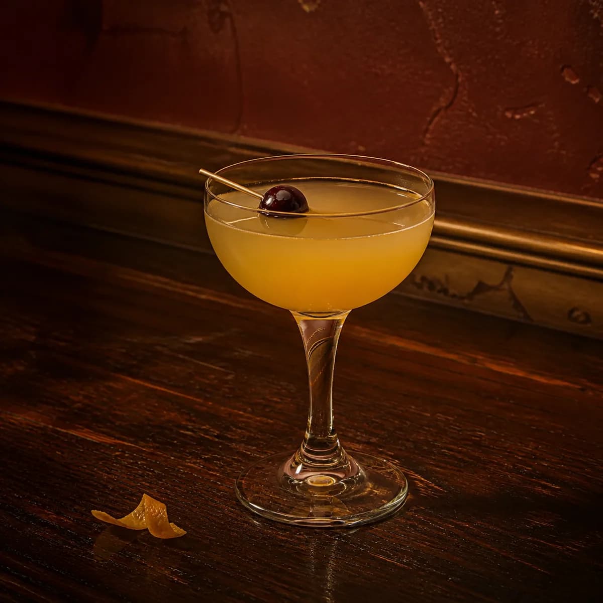 Algonquin in a clear shallow coupe styled in a small jazz bar with oxblood plaster, old brass trim and scratched dark wood.