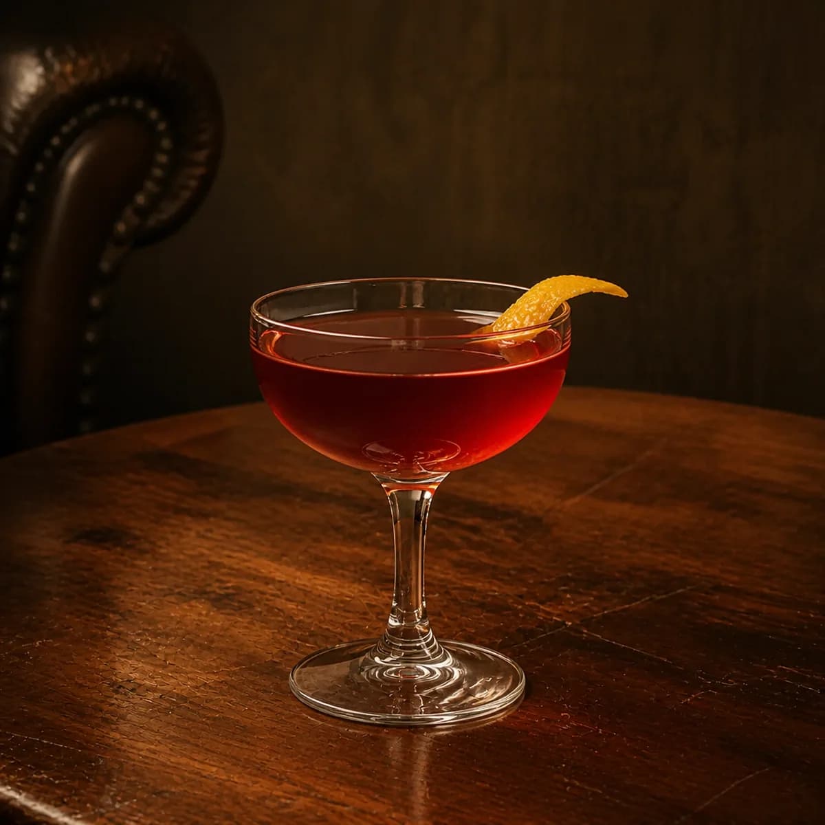 Corpse Reviver #1 in a clear shallow coupe styled in a quiet drawing-room bar with tobacco linen, walnut and one worn leather chair edge.
