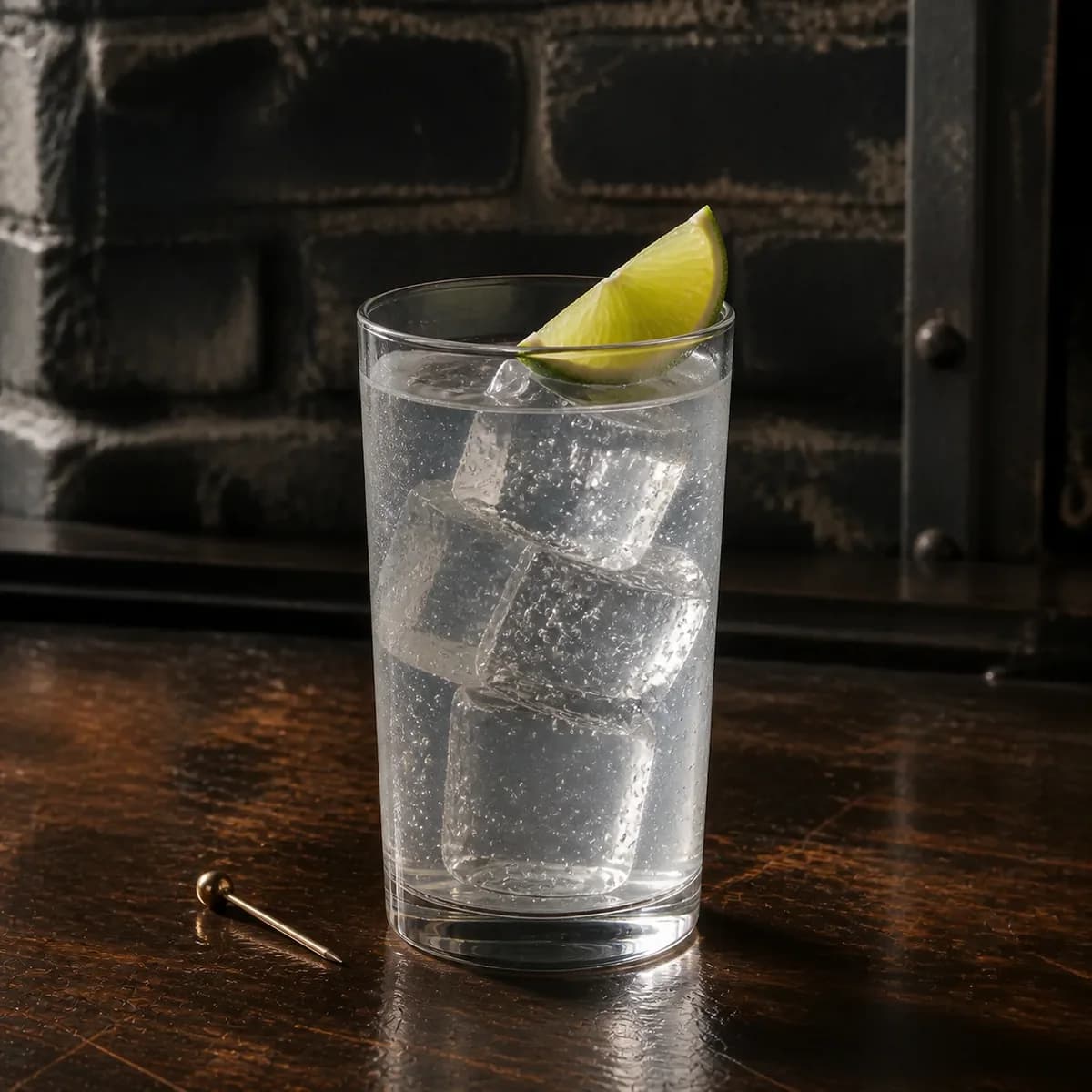 Vodka Soda in a tall straight-sided highball glass styled in a lived-in industrial loft bar with charcoal brick, scratched walnut and aged metal details.