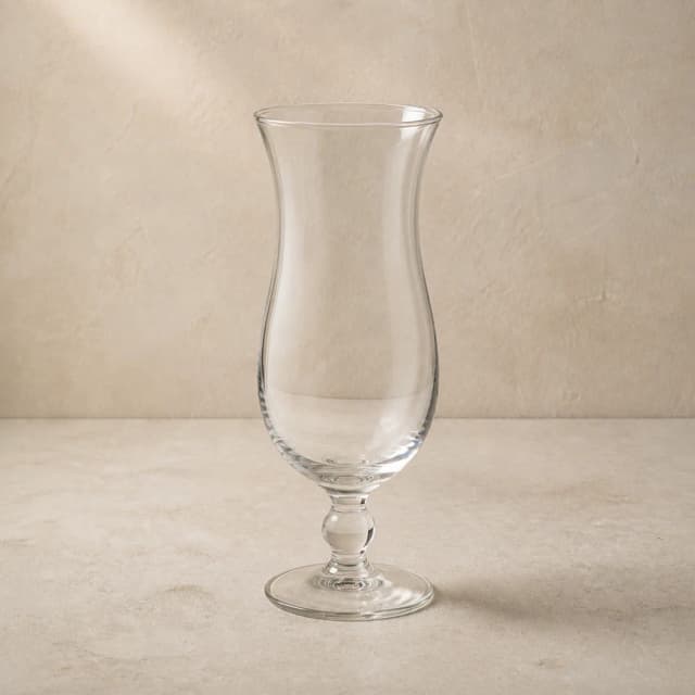 An empty clear hurricane glass with a tall curved bowl, flared rim and short stem.